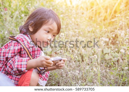 little girl photographs flower outdoor