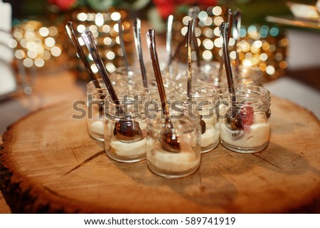 Little bottles with sauces and spoons stand served on wooden dish