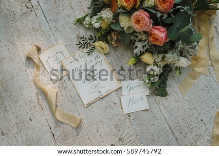 Graphic arts of beautiful wedding calligraphy cards with flower and chiffon bobbins on wood background. Beautiful wedding invitation. Details from fabric and inscription flowers, top view.
