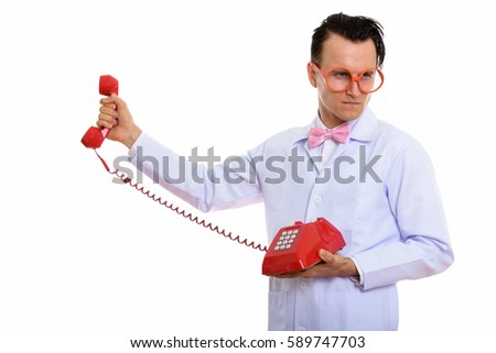Studio shot of young crazy man doctor holding old telephone and looking angry