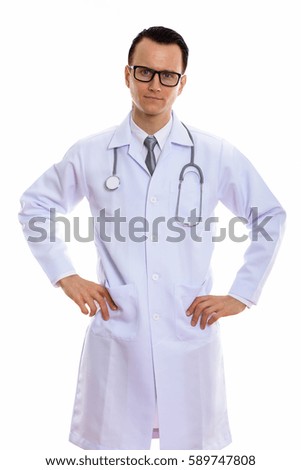 Studio shot of young handsome man doctor standing with hands on hips
