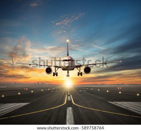 Passengers airplane landing to airport runway in beautiful sunset light, silhouette of modern city on background Royalty-Free Stock Photo #589758764
