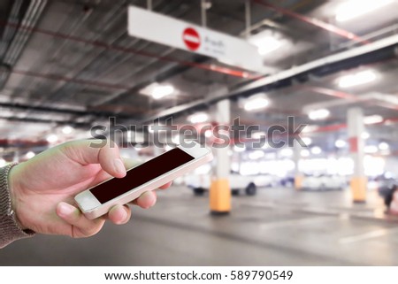 Man use mobile phone, blur image of the car parking in the mall as background.