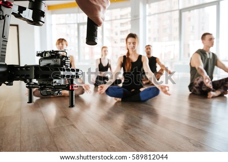 Video shooting of people doing yoga and meditating in studio. Backstage