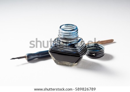opened inkwell and dip pen on rough paper Royalty-Free Stock Photo #589826789