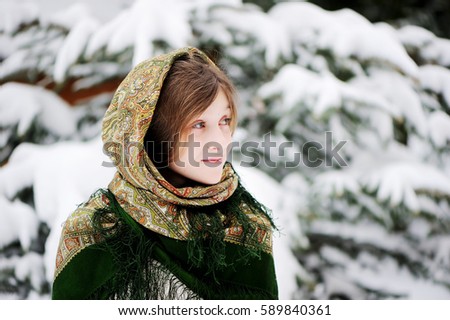 A portrait of russian little girl in classic green Pavlovsky Posad shawl in winter park on beauty