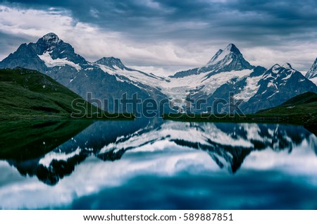 Dramatic summer evening on Bachalpsee lake with Schreckhorn and Wetterhorn peaks on background. Dark outdoor scene in the Swiss Bernese Alps, Switzerland, Europe. 