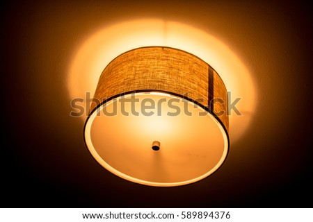 Ceiling Light: A ceiling light glows orange. Royalty-Free Stock Photo #589894376