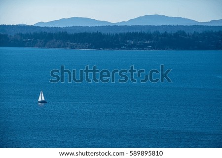 Sailboat: A sailboat is alone in the Puget Sound. Royalty-Free Stock Photo #589895810