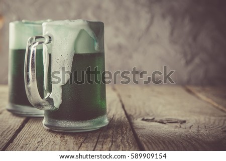 Green beer in mugs on rustic wood background, copy space