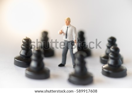 Business and strategy concept. Businessman miniature figure standing on center of circle of chess pieces