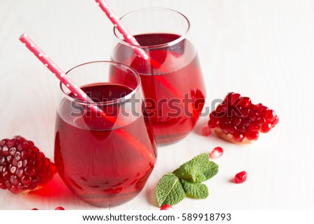 A glass of pomegranate juice with fresh pomegranate fruits on wooden table. Vitamins and minerals. Healthy drink concept.