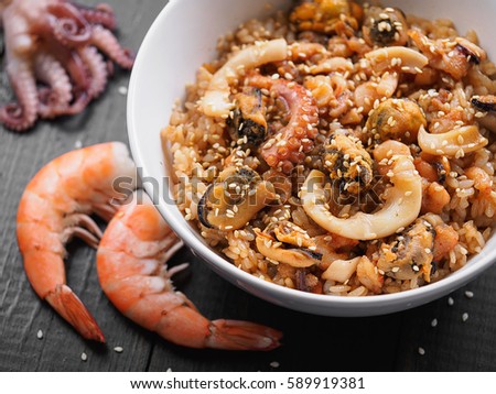Wok rice with meat seafood vegetables on a black wooden table