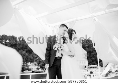 Charming wedding couple hugging on pier of the dock under bungalow. Black and white photo.