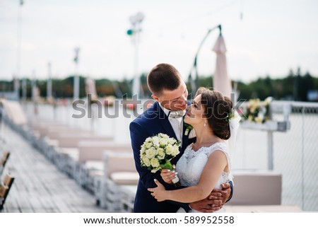 Charming wedding couple hugging on pier of the dock.