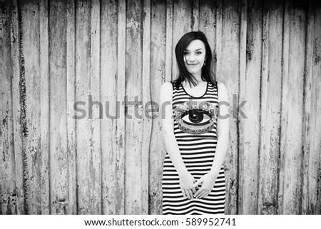 Brunette model girl at dress with stripes background cian wooden background. Black and white photo.