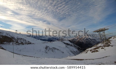 Skiers and snowboarders on the slope in the french alps. Winter landscape with snow covered mountain peaks. Ski resort in France, Europe. Sunset during winter in the mountains. Amazing winter scenery