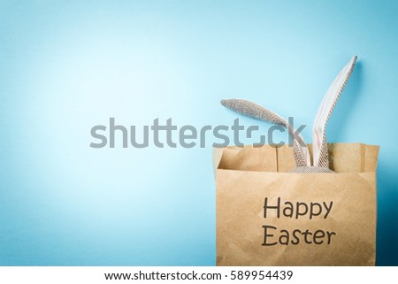 Easter bunny in a paper bag. Rabbit. Blue background. Easter ideas. Space for text. Black lettering happy easter.