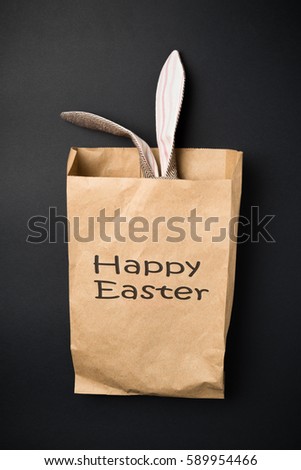 Easter bunny in a paper bag. Rabbit. Black background. Easter ideas.  Space for text. Black lettering happy easter.