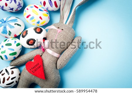 Easter bunny on a blue background with Easter eggs. Rabbit. Space for text. Black lettering on a heart .