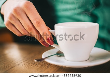 Female hands hold a coffee cup closeup 