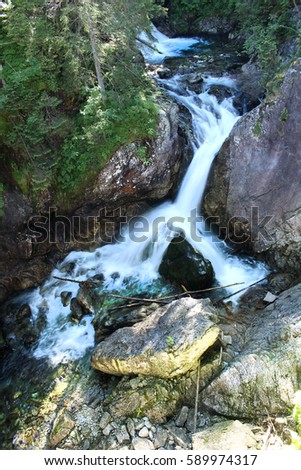 Beautiful waterfall surrounded by green forest with moss and rocks. Wonderful landscape.
