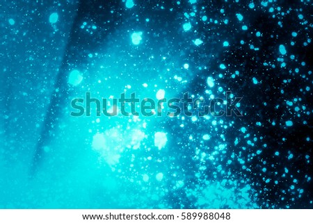 Abstract bokeh or glitter lights on blue  background. Circles and defocused particles. Design template.