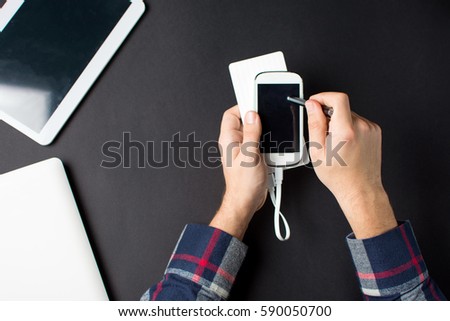 Man using a white cellphone connected to a power bank