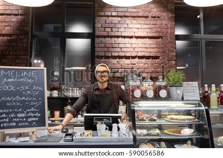 small business, people and service concept - happy seller man or barman at counter with cashbox in vegan cafe or coffee shop