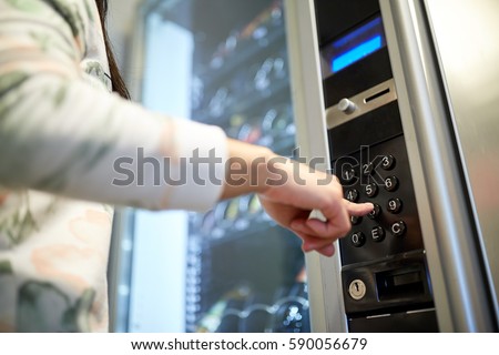 sell, technology and consumption concept - hand pushing button on vending machine operation panel keyboard Royalty-Free Stock Photo #590056679