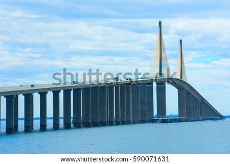 Unique angle of the famous Sunshine Skyway Bridge over Tampa Bay Florida with many vehicles on it and fishing boats under it.