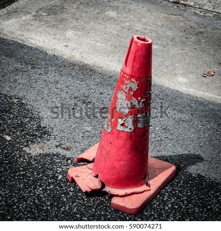 Broken red plastic cone on the asphalt road