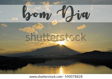 Image with text BOM DIA, Portugese word for good morning with beautiful sun rising grandly from behind a mountain. Concept idea for greeting, tourism, language teaching and for background purposes.