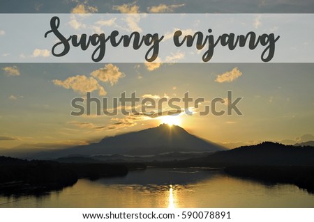 Image with the text SUGENG ENJANG, Javanese word for good morning with beautiful sun rising from behind a mountain. Concept idea for greeting, tourism, language teaching and for background purposes.