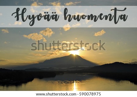 Image with the text HYVAA HOUMENTA, Finnish word for good morning with beautiful sun rising from behind a mountain. Concept idea for greeting, tourism, language teaching and for background purposes.