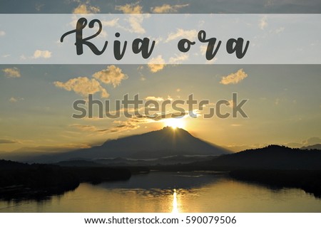 Image with the text KIA ORA, Maori word for good morning with beautiful sun rising grandly from behind a mountain. Concept idea for greeting, tourism, language teaching and for background purposes.