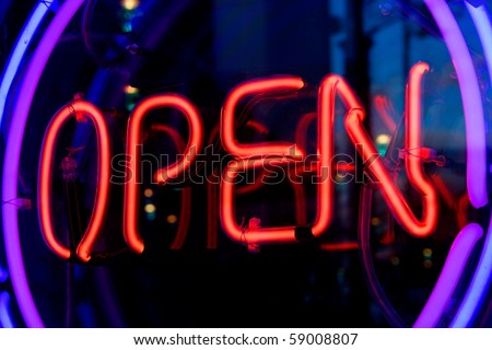 Blue, purple and red neon sign of the word 'Open' inside two rings of lighting, on a black background.