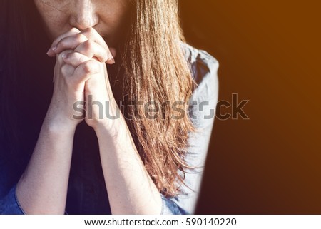 Woman praying in meadow at sunset with gradient Royalty-Free Stock Photo #590140220