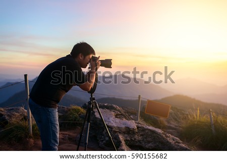 Photographer silhouette above a clouds sea, misty mountains in twilight time