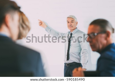 Senior Businessman Explaining Table to Audience
