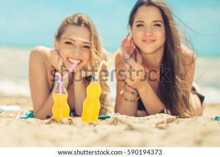 Beautiful young girls drinking water from boutle on the beach
