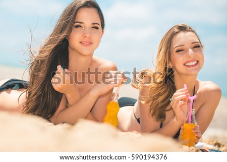 Beautiful young girls drinking water from boutle on the beach