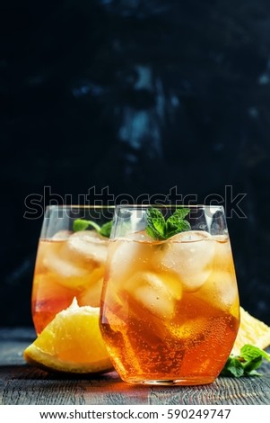 Orange cocktail with ice, black background, selective focus