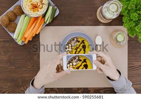 Vegan man doing soup photo with his smartphone during lunch