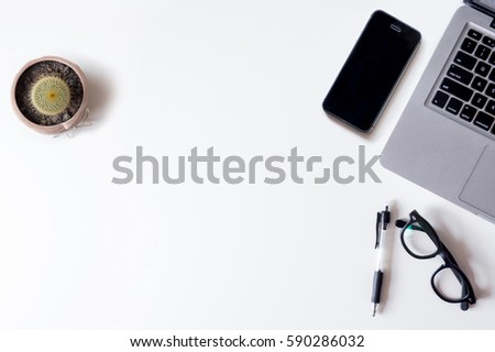 White office desk table with laptop, smartphone, and cactus. Top view with copy space, flat lay.