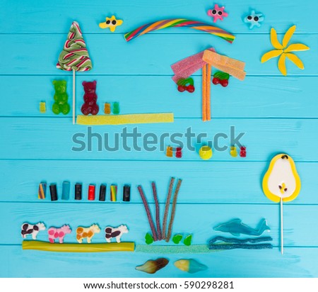 Cheerful picture of tasty jelly candies in the shape of bears, cows, strawberries, cherries and trees on wooden turquoise table