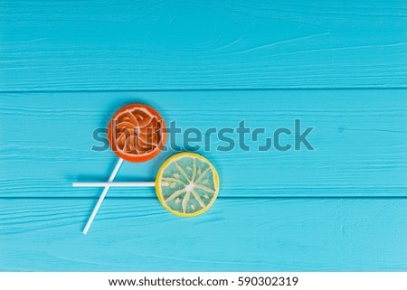 Small lollipops as an orange and lemon on wooden turquoise board