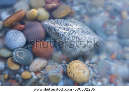 Long exposure of the sea on various colored pebbles