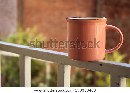 Cup of coffee on the white fence. French style. Beautiful background in early spring. Pink mug in the morning.