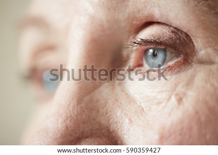 Sad blue-grey eyes of elderly woman looking to the side, extreme close-up shot Royalty-Free Stock Photo #590359427